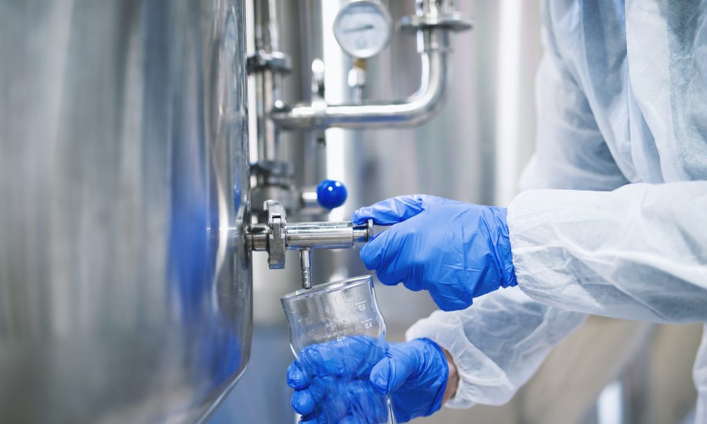 close-up-view-hands-protective-gloves-opening-tap-valve-filling-glass-with-samples-from-industrial-machine-reservoir